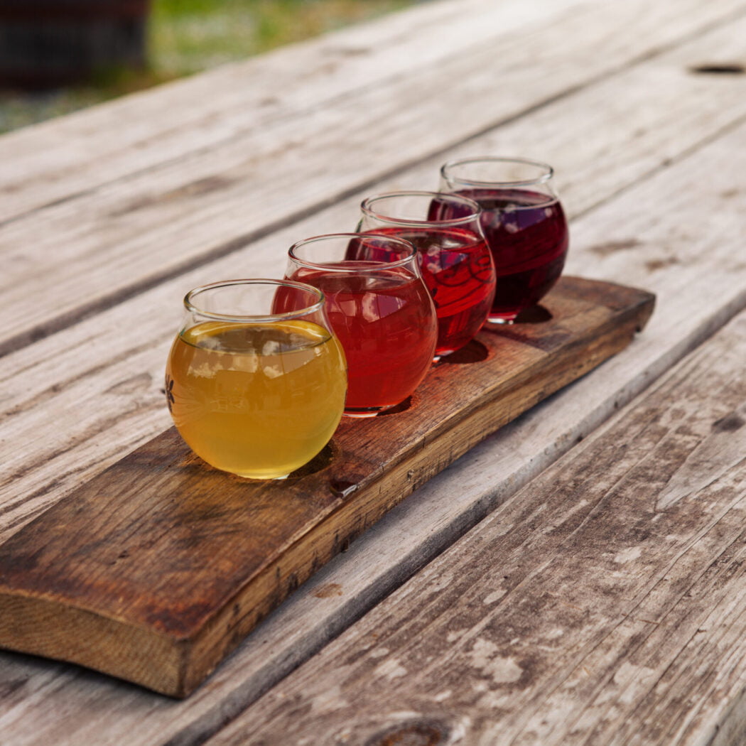 Flight of sustainably produced craft Ciders served on a reused barrel stave. colorful, natural, drinks